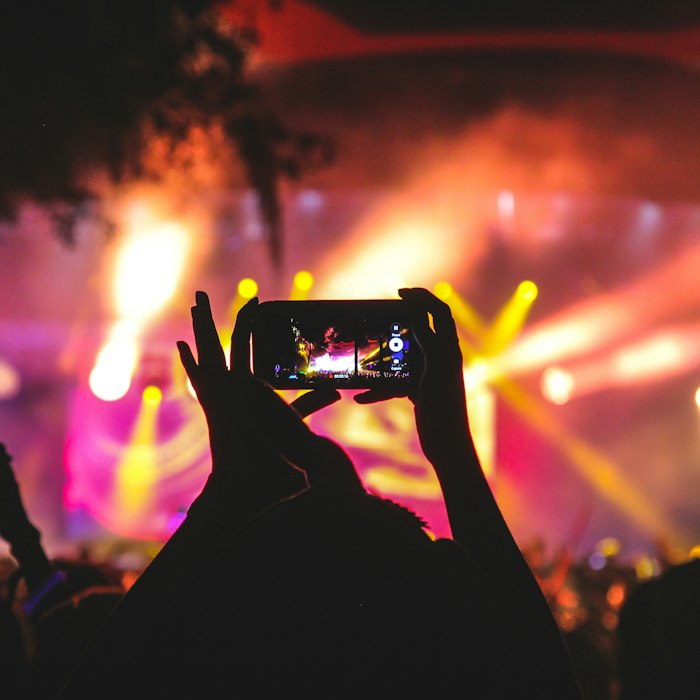 Audience filming a concert under stage lights